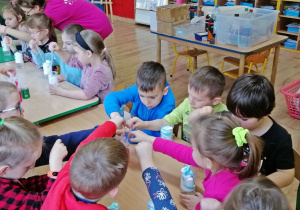 Dzieci nabierają pipetą kolorowe barwniki